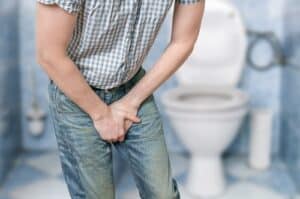 Incontinence problem of a Man in front of toilet bowl.